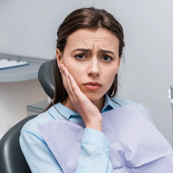 upset woman touching face while having toothache and looking at camera